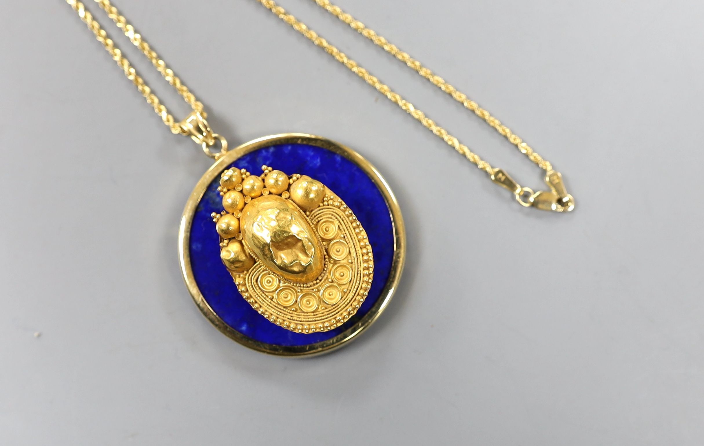 An Egyptian yellow metal earring from the Josephine Dubois Collection, now mounted on a 14l and lapis lazuli circular pendant, with a 14k chain